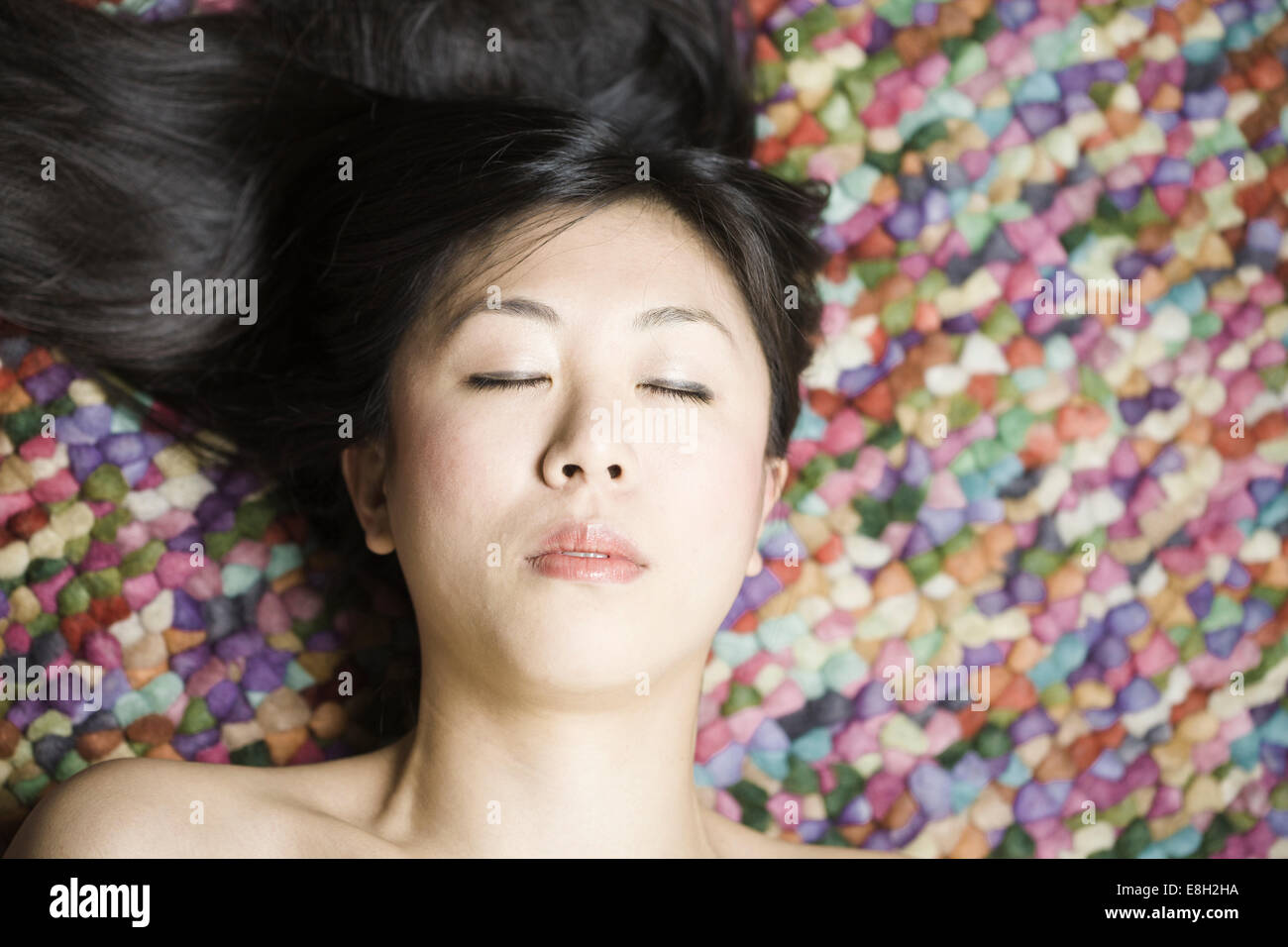 Portrait of Asian woman with closed eyes in front of colourful ground ...