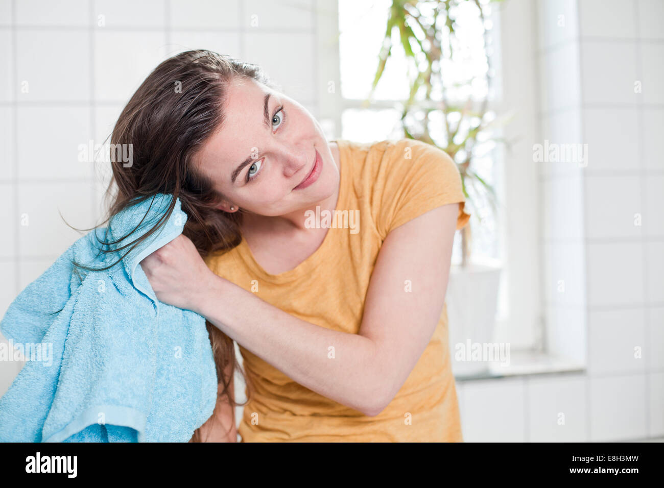 Portrait of young woman drying her hair with towel in the bathroom ...