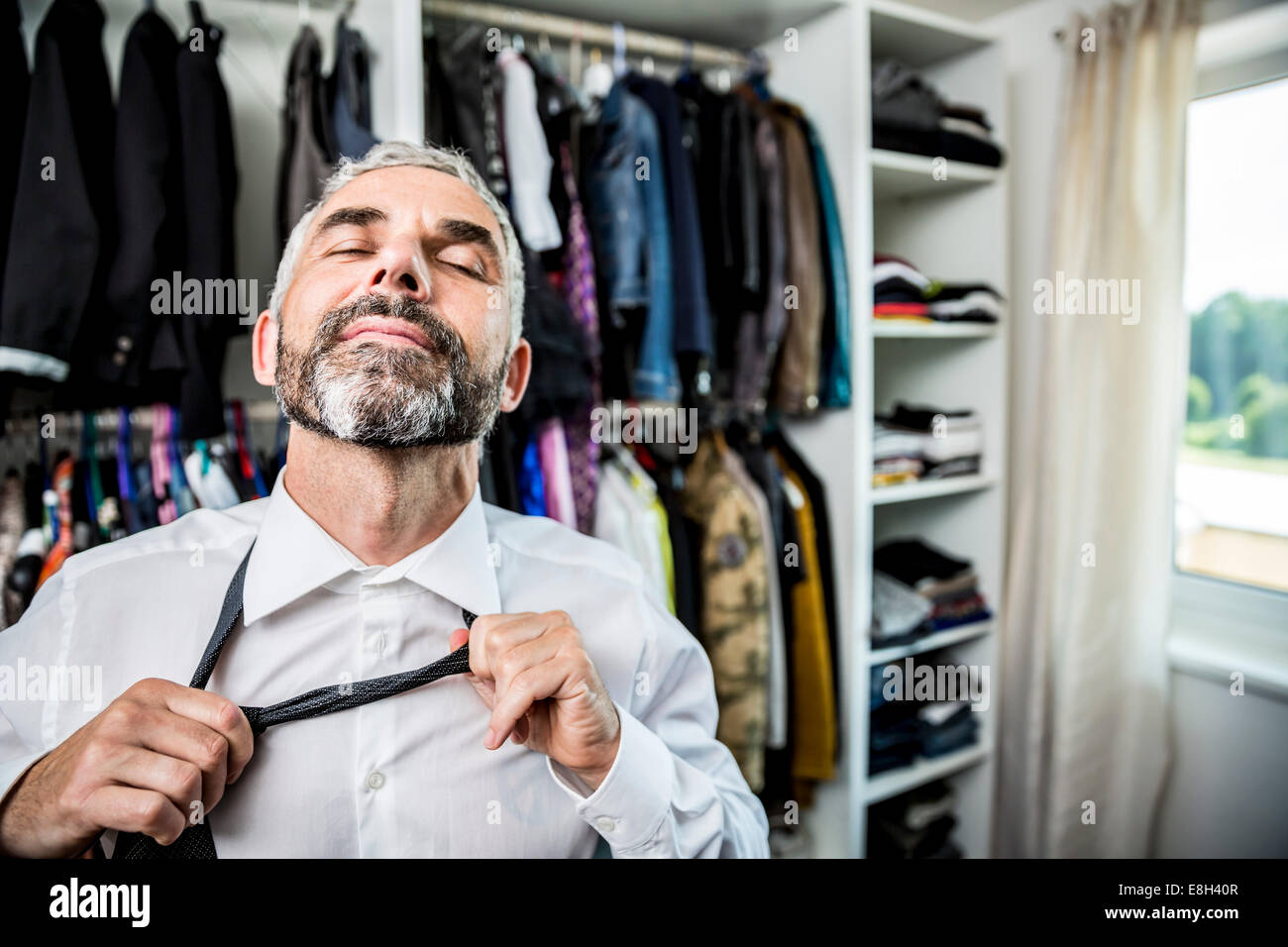 Businessman binding tie at his walk-in closet Stock Photo