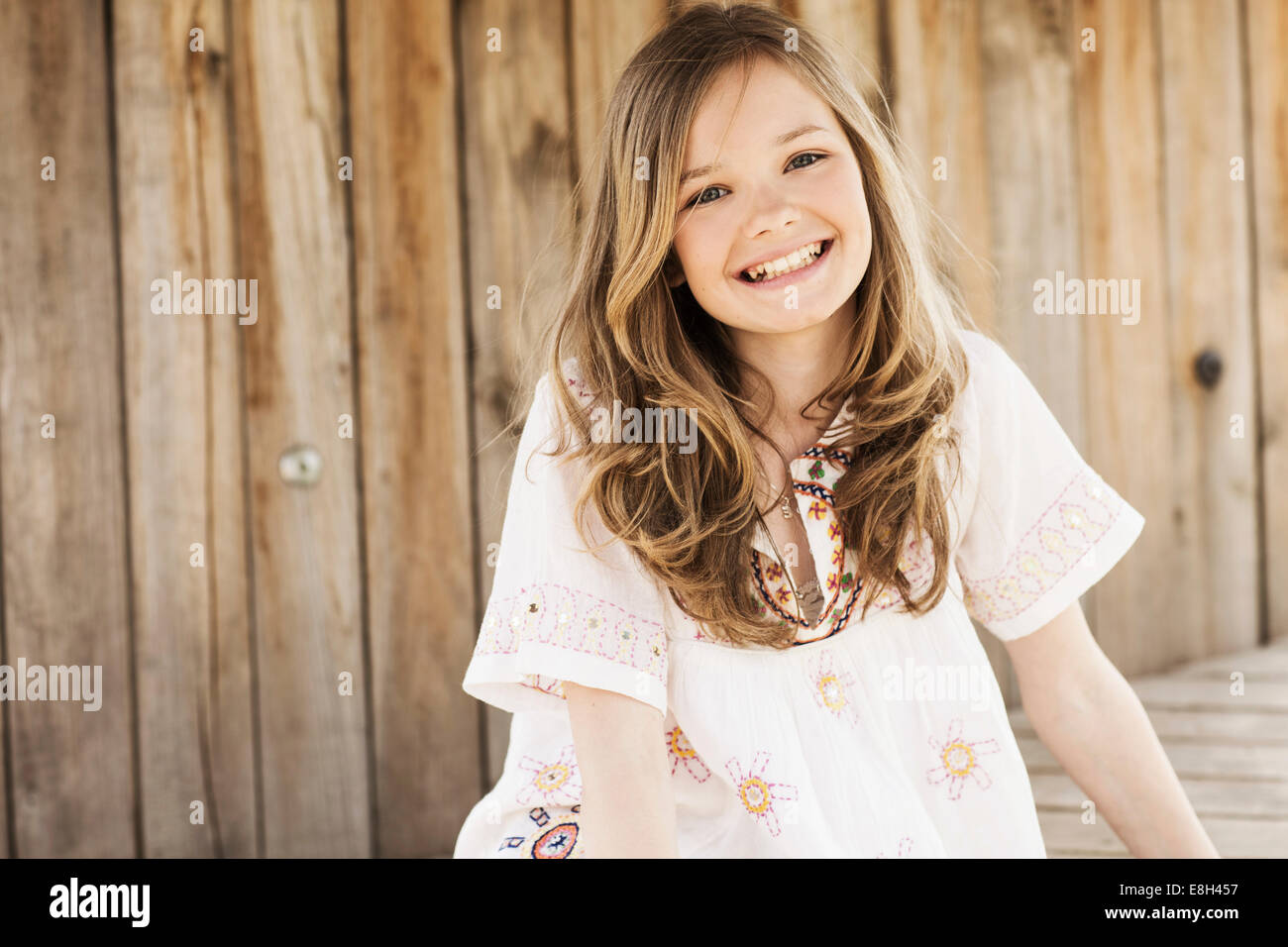 Portrait of smiling girl in front of wooden wall Stock Photo - Alamy