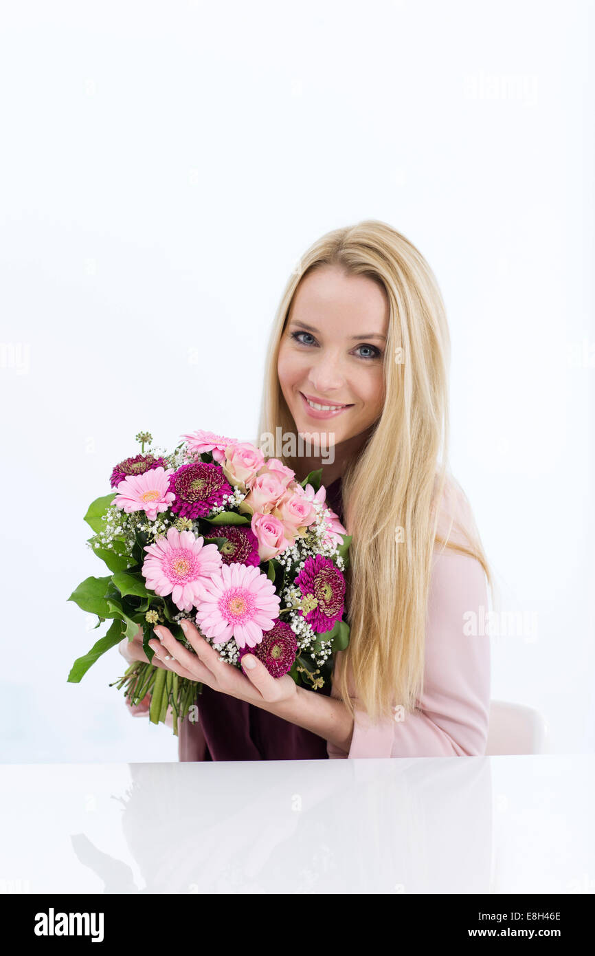Portrait of smiling young woman holding bunch of flowers Stock Photo ...