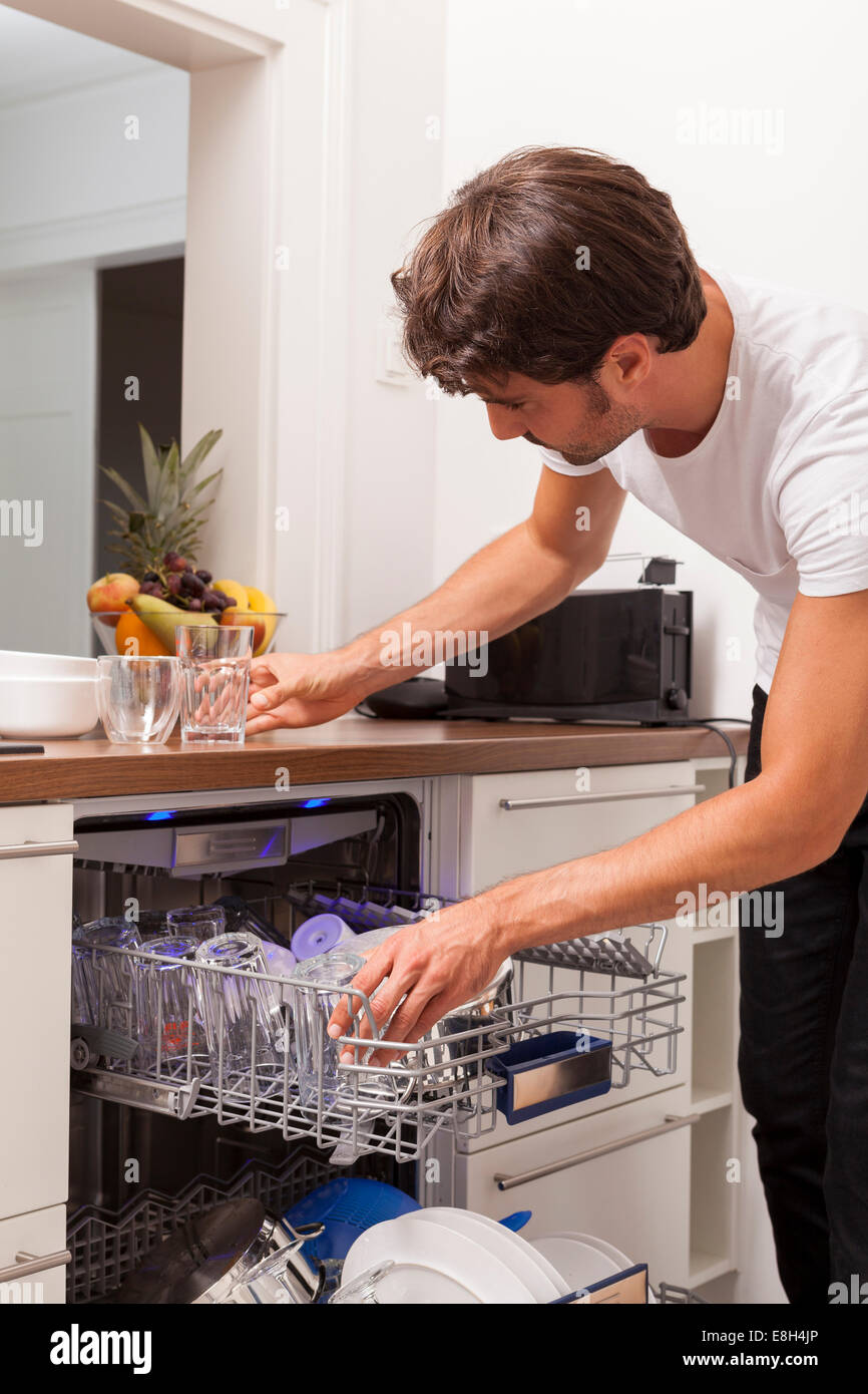 Smiling young man emptying the dishwasher Stock Photo