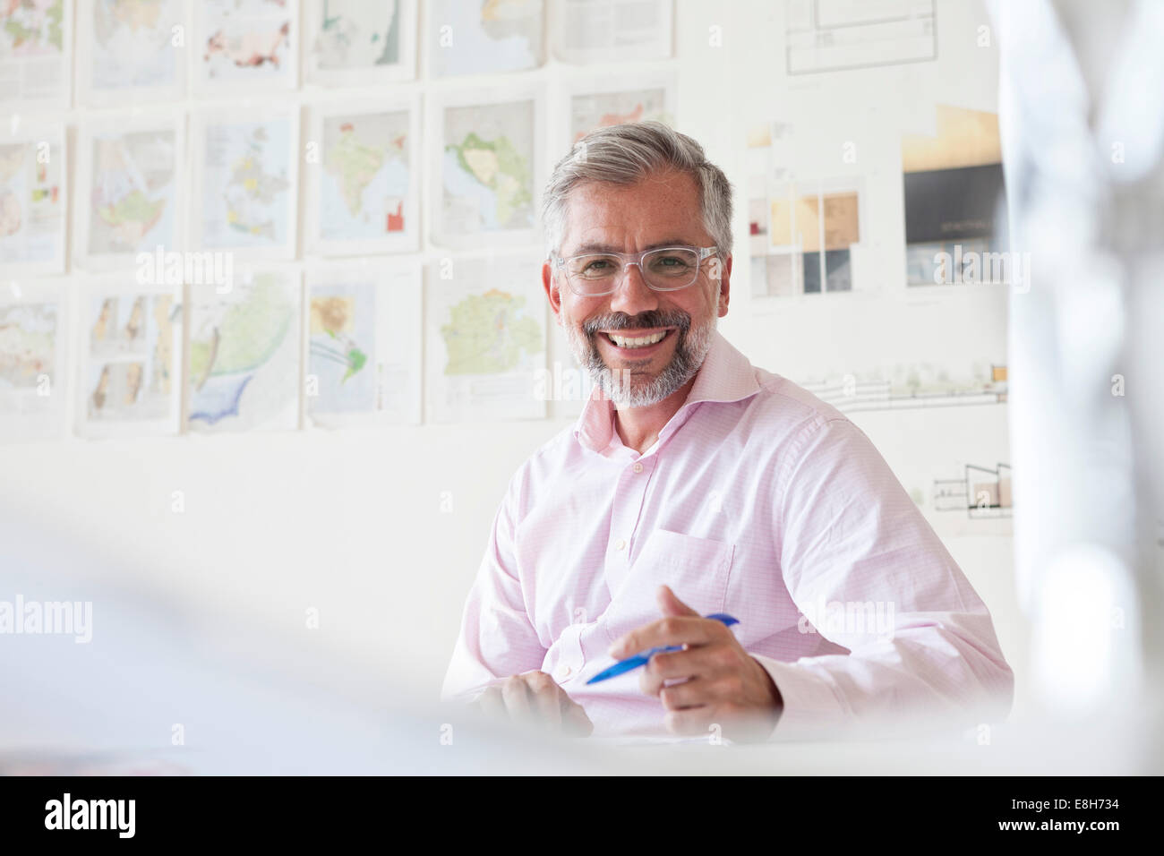 Portrait of smiling businessman sitting at his desk in an office Stock ...