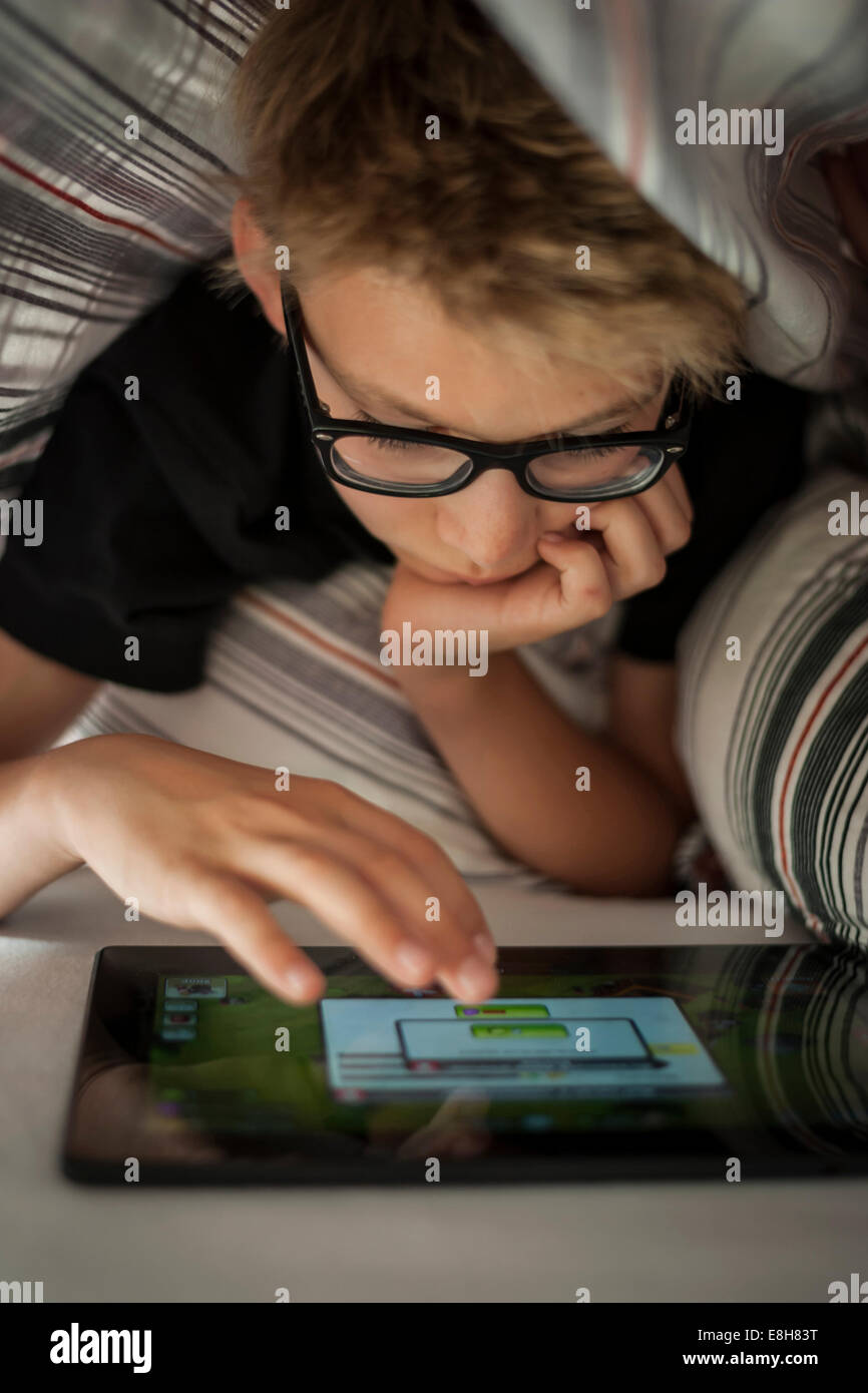 Boy lying on bed using digital tablet Stock Photo - Alamy