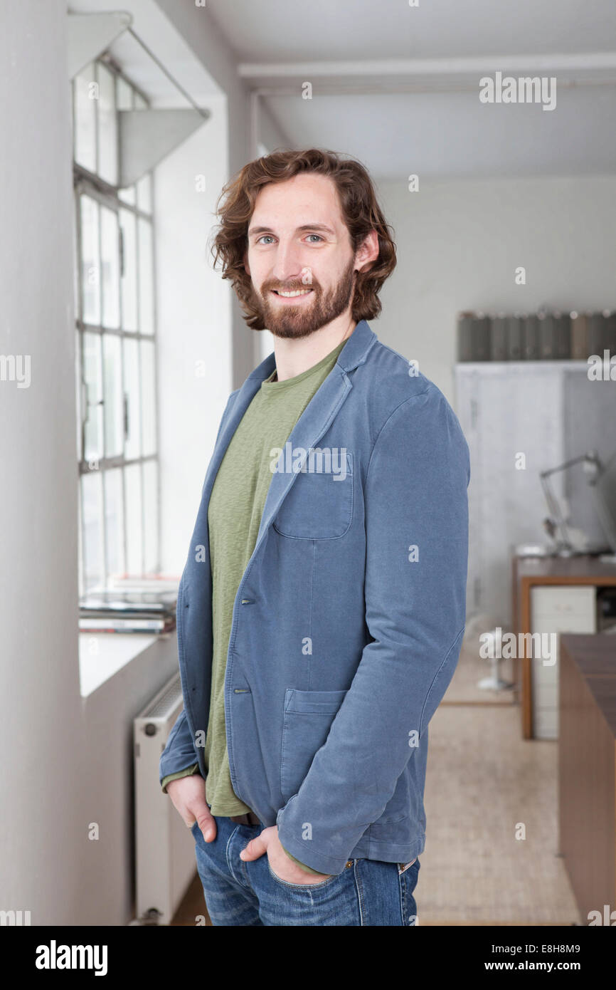 Portrait of smiling young man standing in an office Stock Photo - Alamy