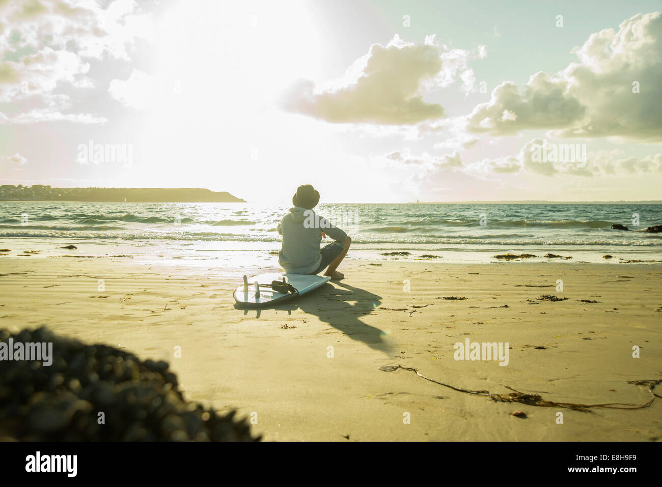 Teenage boy sitting on the beach watching sunset Stock Photo - Alamy