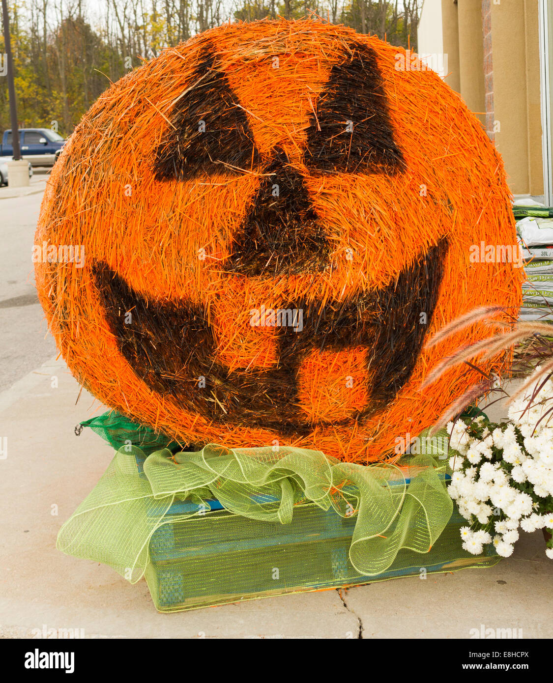 Round bale of hay painted to look like a hallowe'en pumpkin or jack-o-lantern. Stock Photo