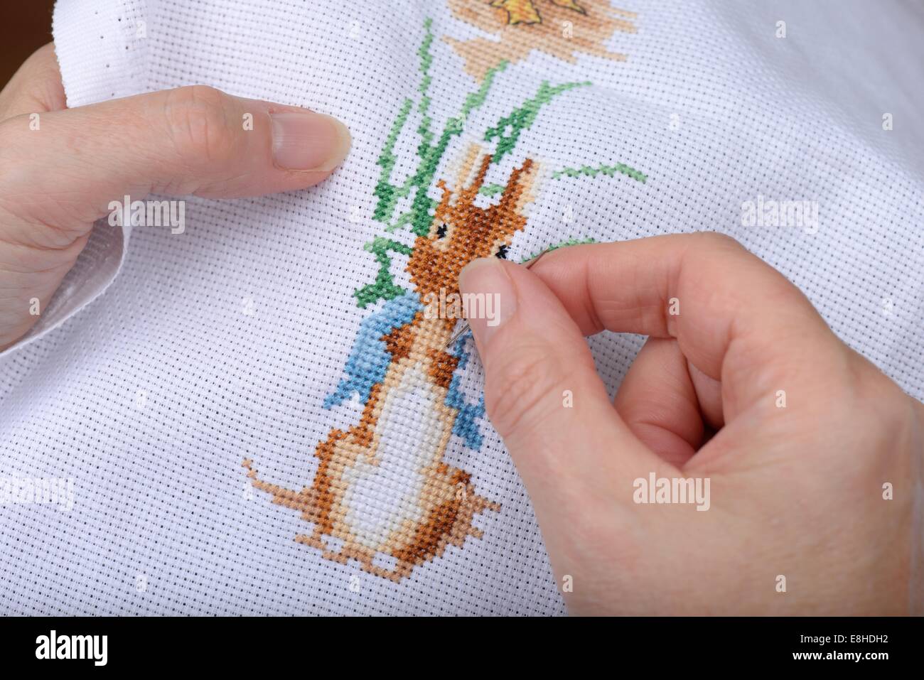 Close-up of woman's hands cross stitching with needle and thread. Stock Photo