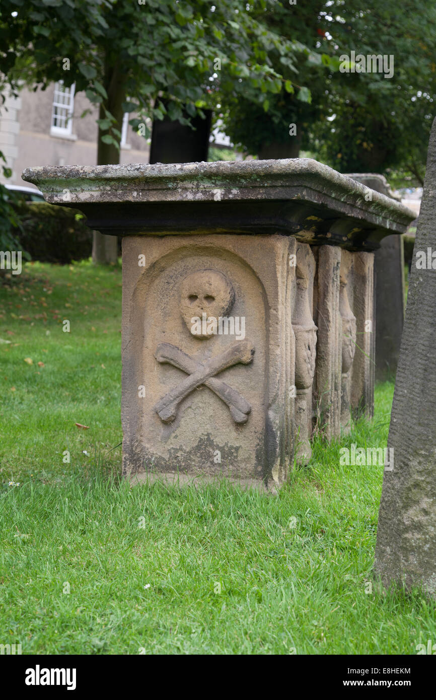 Church graveyard at Eyam Derbyshire Peak District England United Kingdom showing plague headstone with skull and cross bones Stock Photo