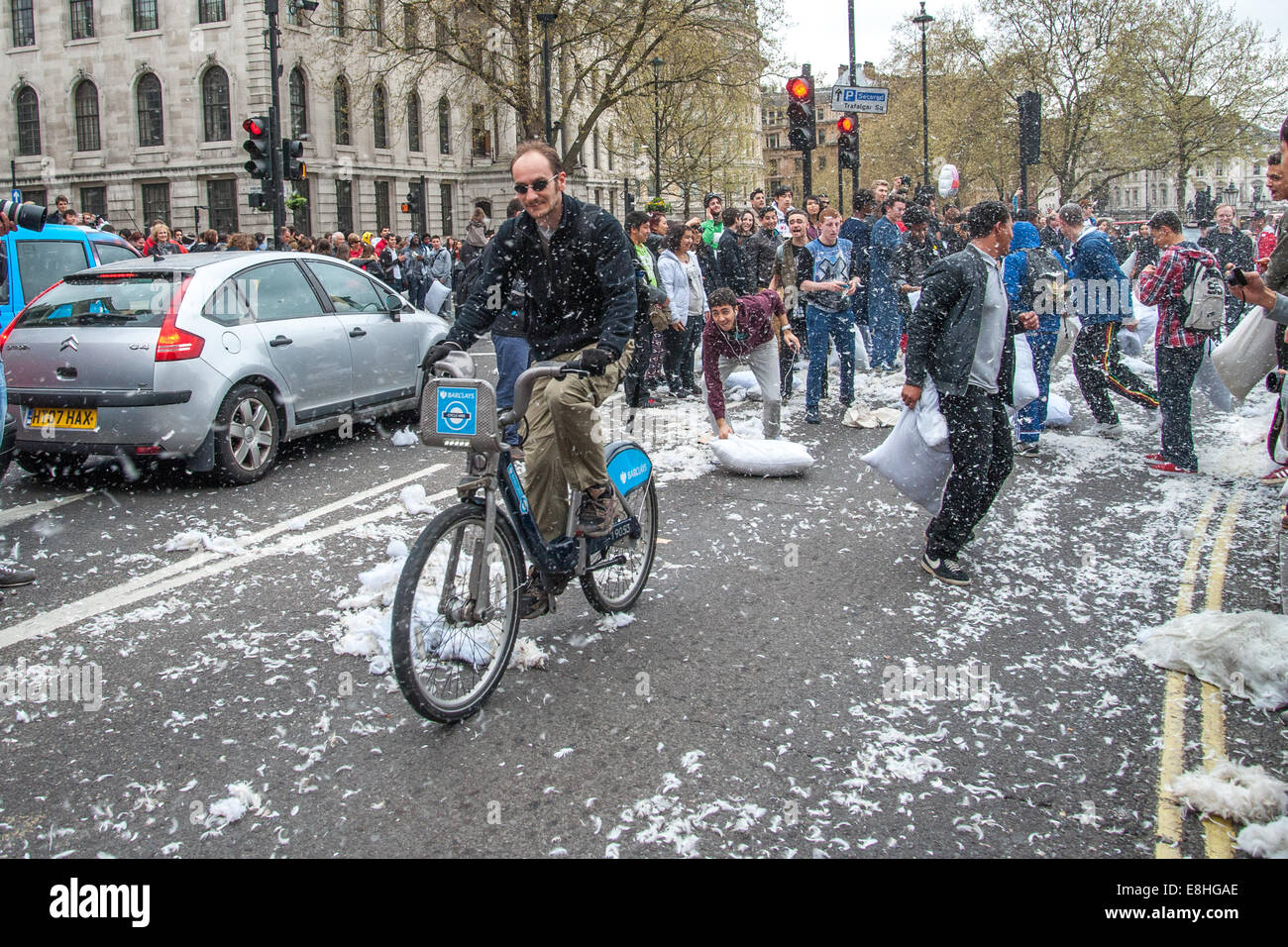 A cyclist on a Boris Bike rides through the commotion as Londoners pillow fight in the street around Trafalgar Square during International Pillow Fight Day 2014  Where: London, England, United Kingdom When: 05 Apr 2014 Stock Photo