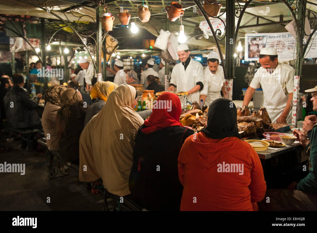 Horizontal view of a group of Muslim women eating in Place Jemaa el Fna (Djemaa el Fnaa) in Marrakech at night. Stock Photo