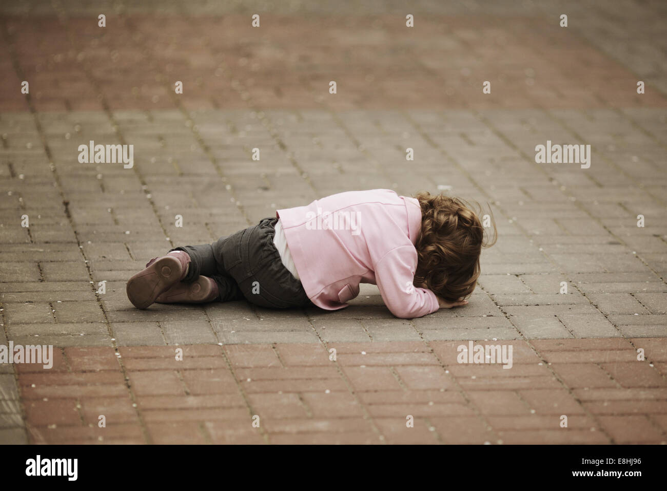 crying girl lying on asphalt Stock Photo