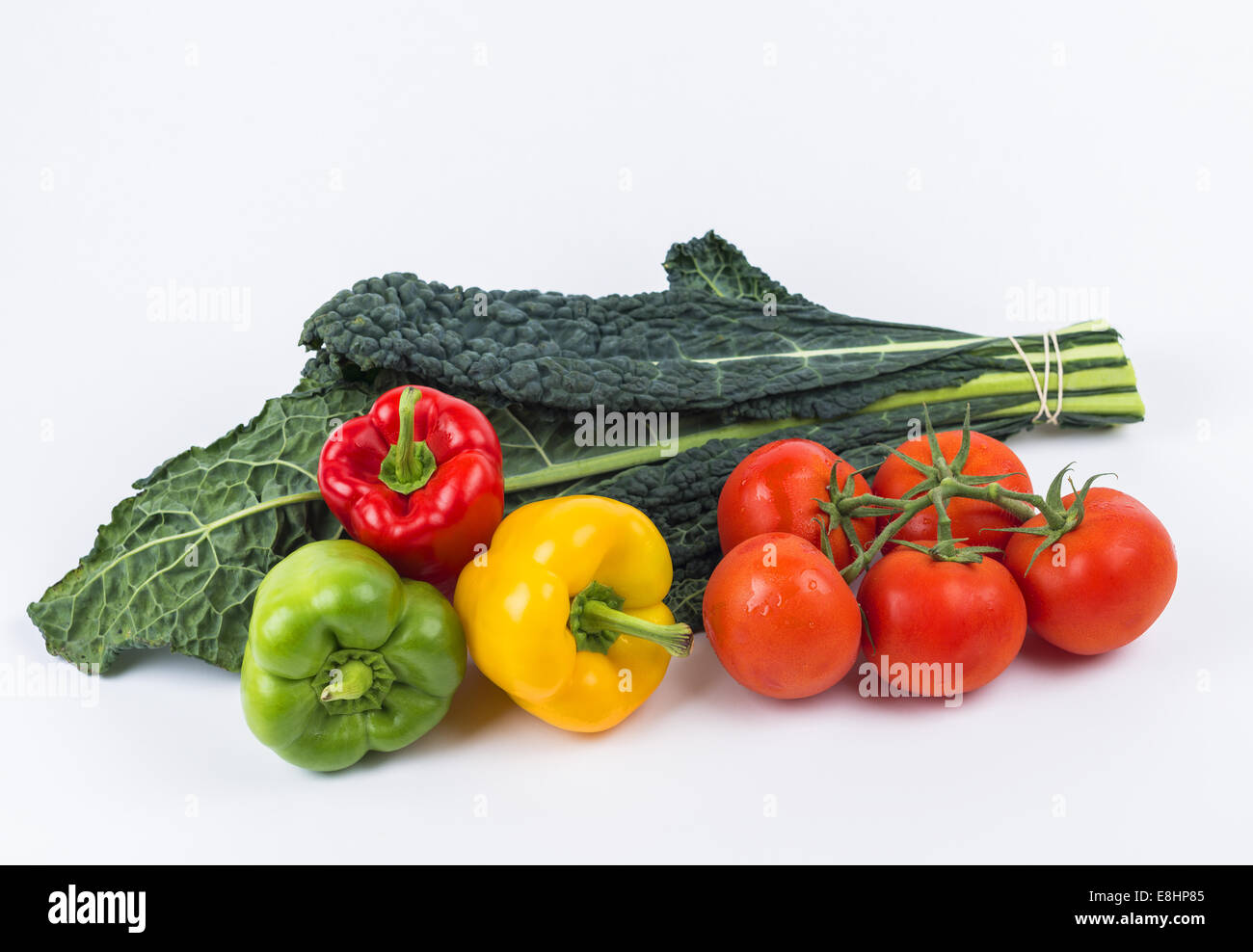 Mixed fruit and vegetables kale leaves red green yellow peppers tomatoes on stem Stock Photo
