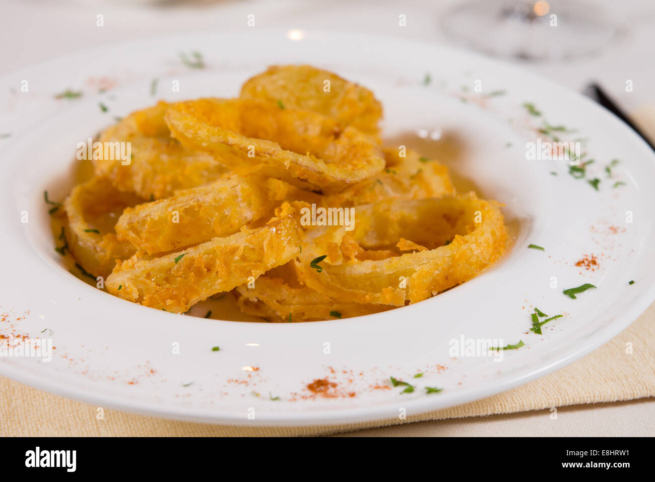 Close up Tasty Fried Onion Rings on White Plate Served on Table. Stock Photo