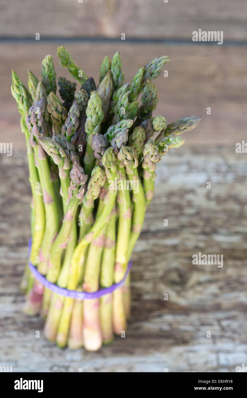 bunched asparagus, with purple tie, with rustic wood background, outdoors  shot from the side Stock Photo