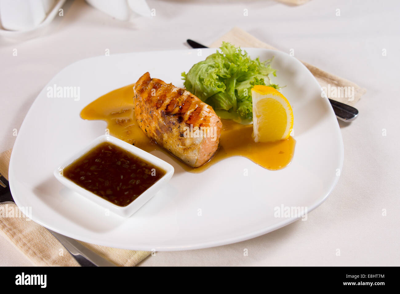 Plated Meal of Grilled Fish with Garnishes at Restaurant Place Setting Stock Photo