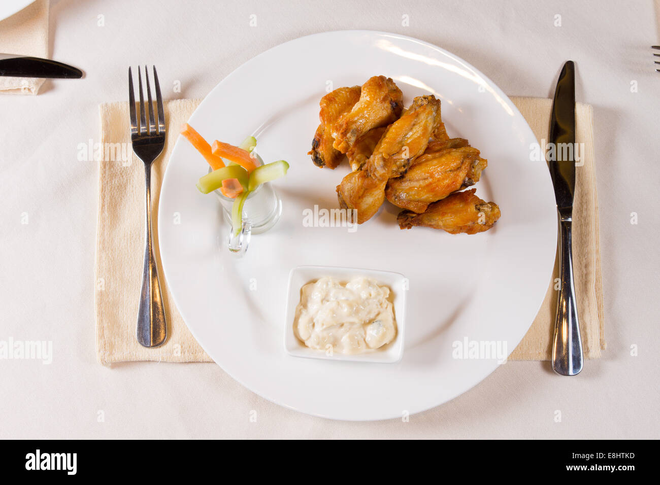 Overhead of Chicken Wings on Plate at Place Setting in Restaurant Stock Photo