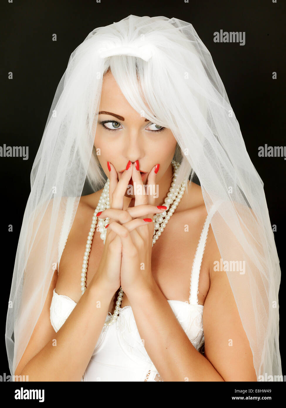 Young Woman Bride To Be Wearing A White Wedding Veil Anticipating A New Life And Beginning In A Life Partnership Isolated Against A Black Background Stock Photo