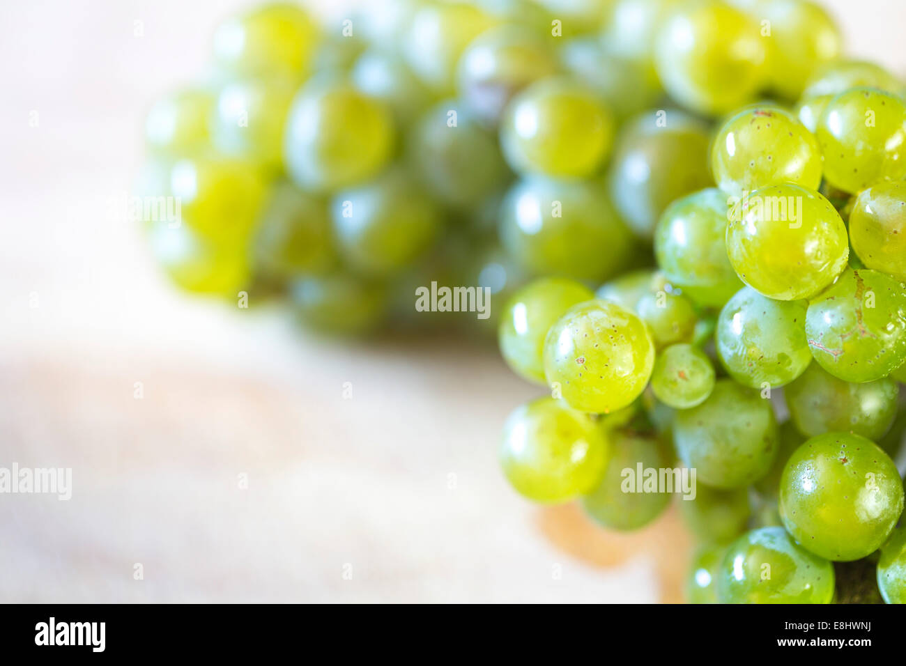 bunch of green grapes on light coloured wooden board with text space on left Stock Photo