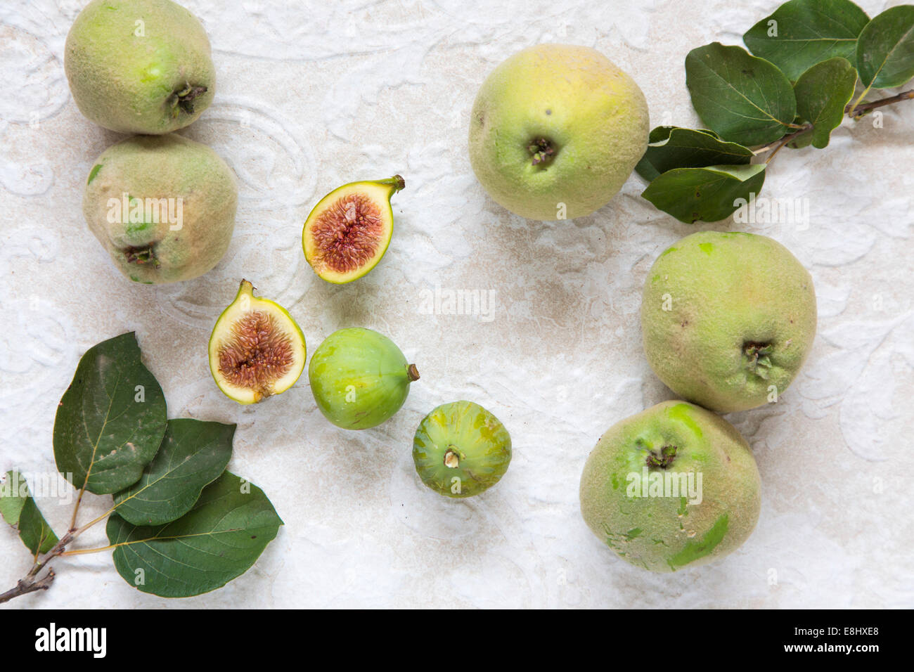 wild quinces and figs, with quince leaves on cream textured background Stock Photo