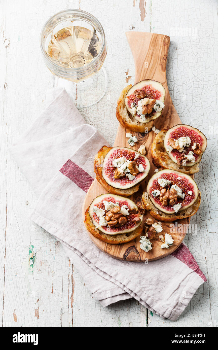 Bruschettas with figs, Blue cheese and walnuts on grilled crusty bread on wooden background Stock Photo