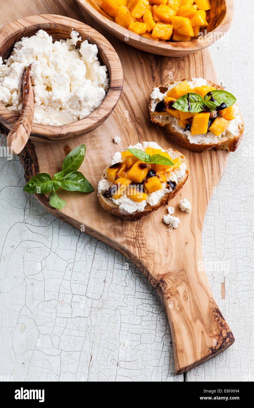 Bruschetta with chopped mango, basil and goat cheese on fresh baguette Stock Photo