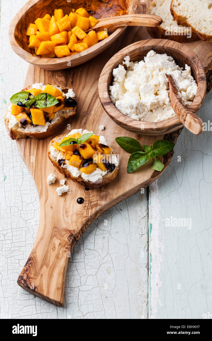 Bruschetta with chopped mango, basil and goat cheese on fresh baguette Stock Photo