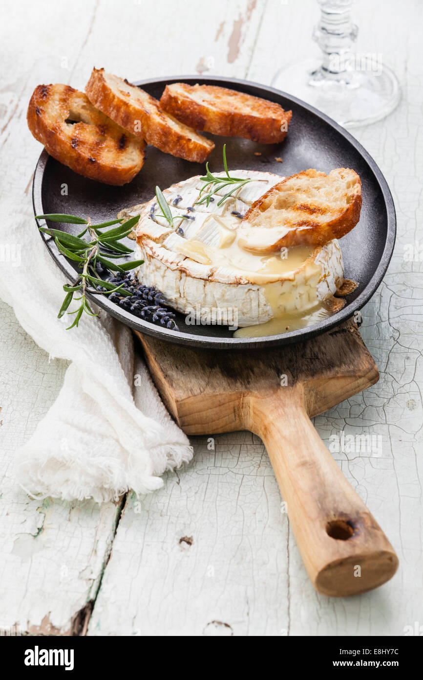 Baked Camembert cheese with toasted bread on cast-iron frying pan Stock Photo