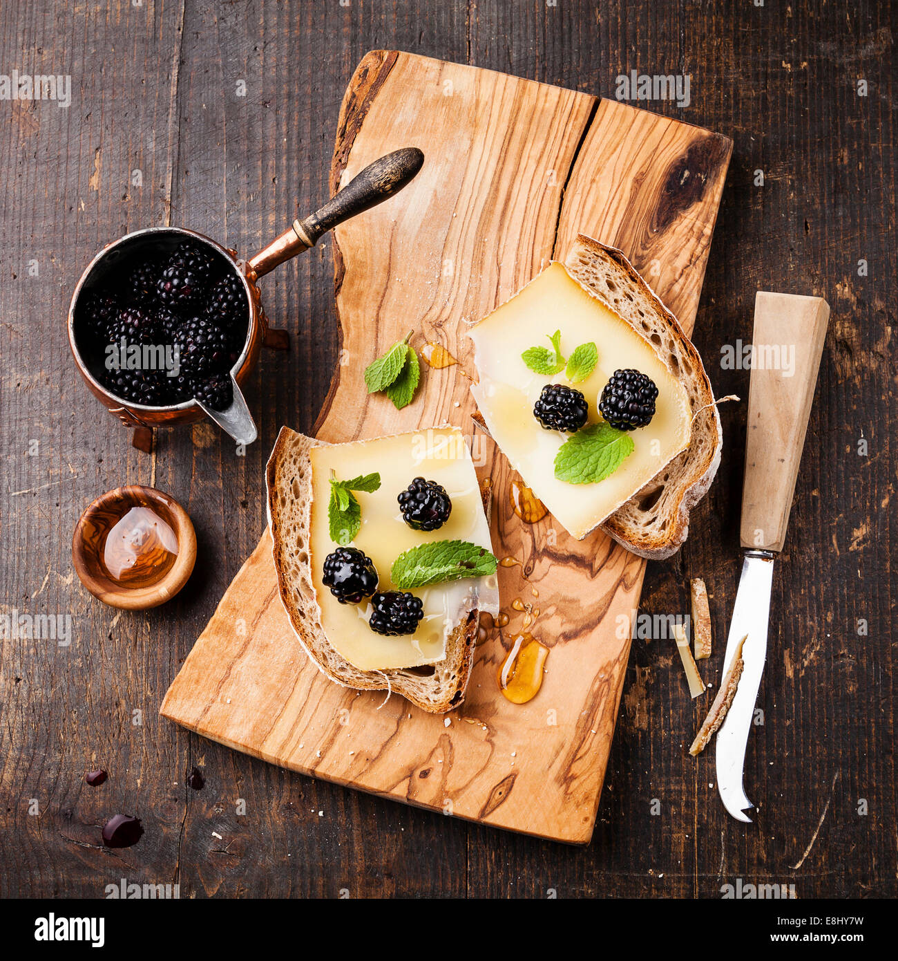 Italian bruschetta sandwich with cheese and blackberry on fresh bread on dark wooden background Stock Photo