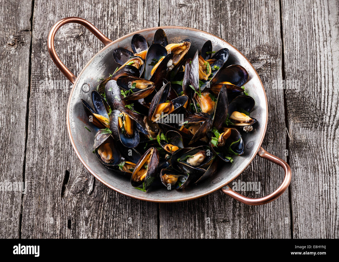 Boiled mussels in copper cooking dish on dark wooden background Stock Photo
