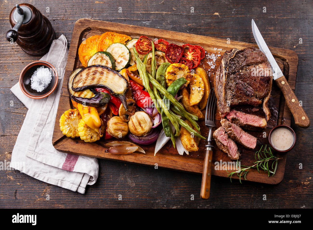 Club Beef steak with pepper sauce and Grilled vegetables on cutting board on dark wooden background Stock Photo