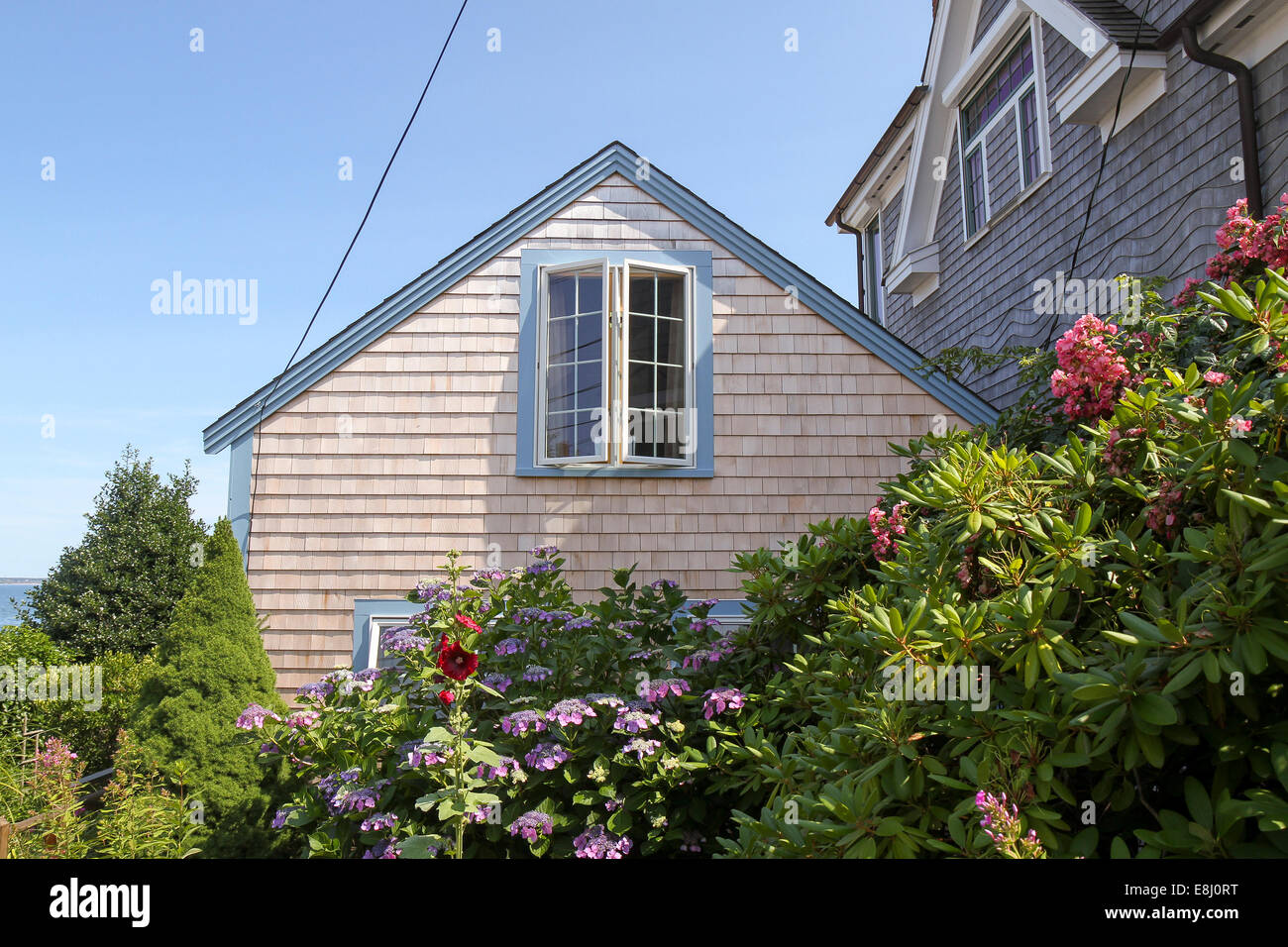 Flowers frame a view of a peaked roof and open window in Provincetown, Massachusetts Stock Photo