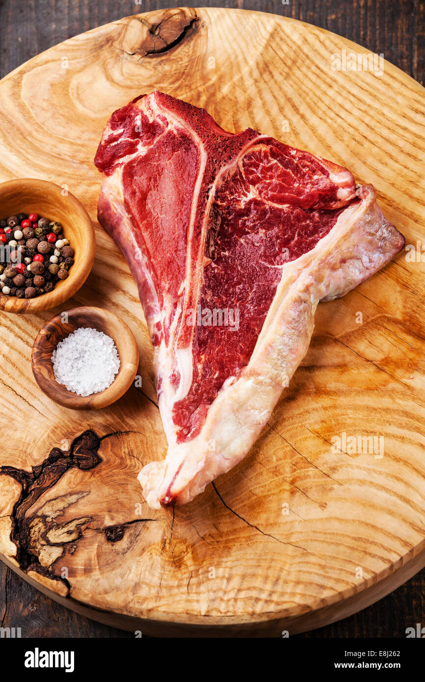 Raw fresh meat TBone Steak with salt and pepper on wooden background