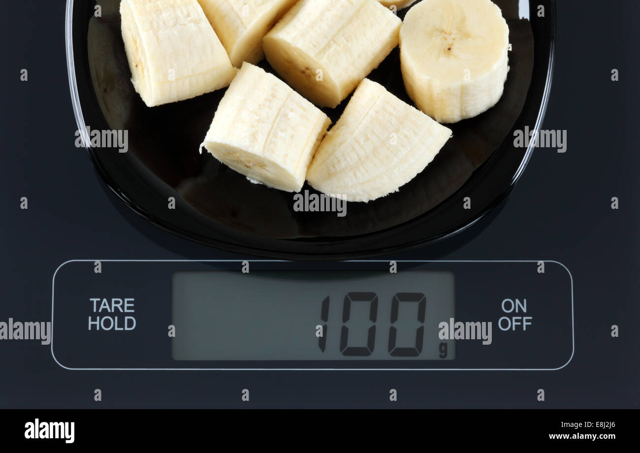 Peeled sliced banana in a black plate on digital scale displaying 100 gram  Stock Photo - Alamy