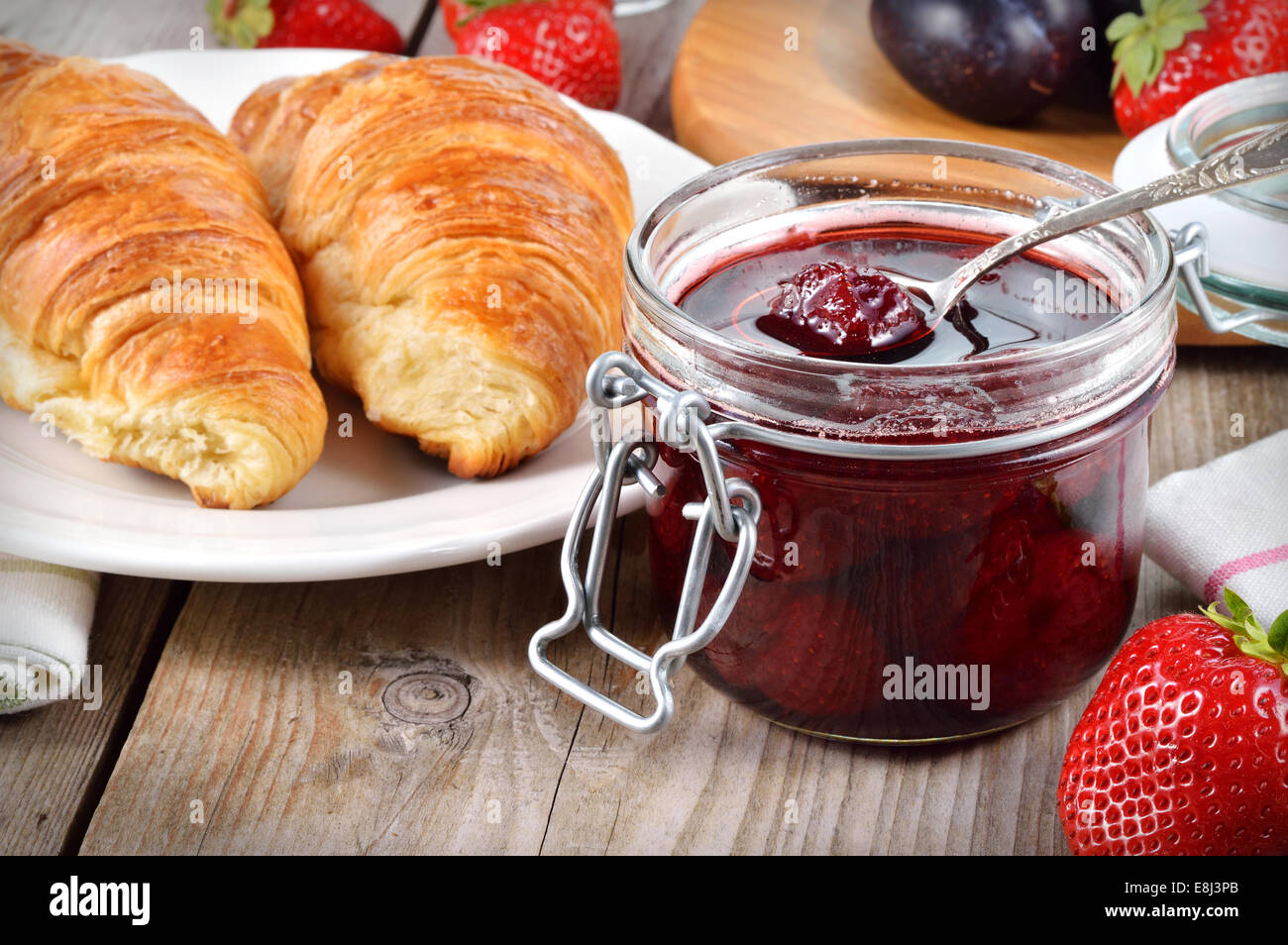 Strawberry jam and croissant on wooden table. Stock Photo