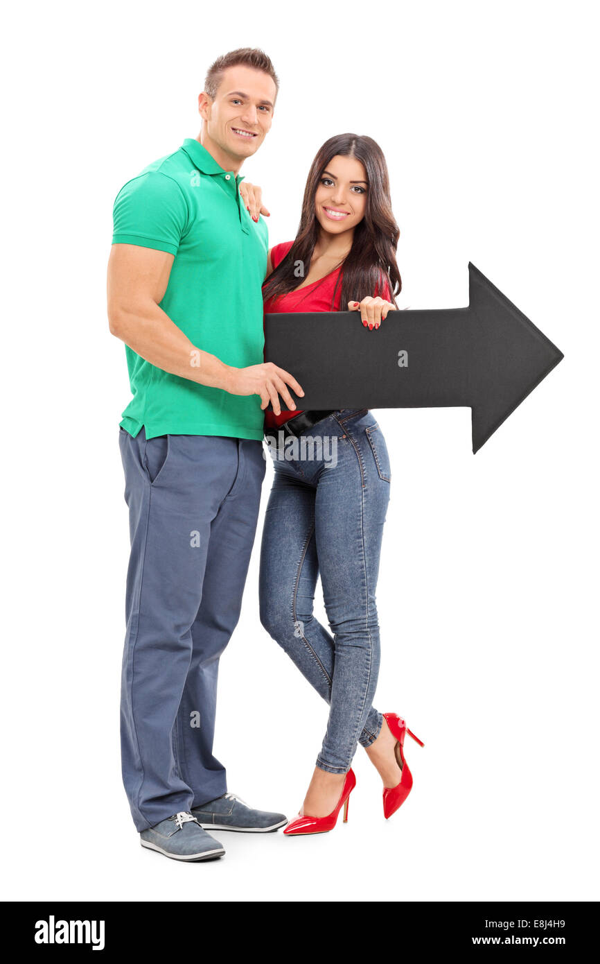 Full length portrait of a young couple holding an arrow pointing right ...