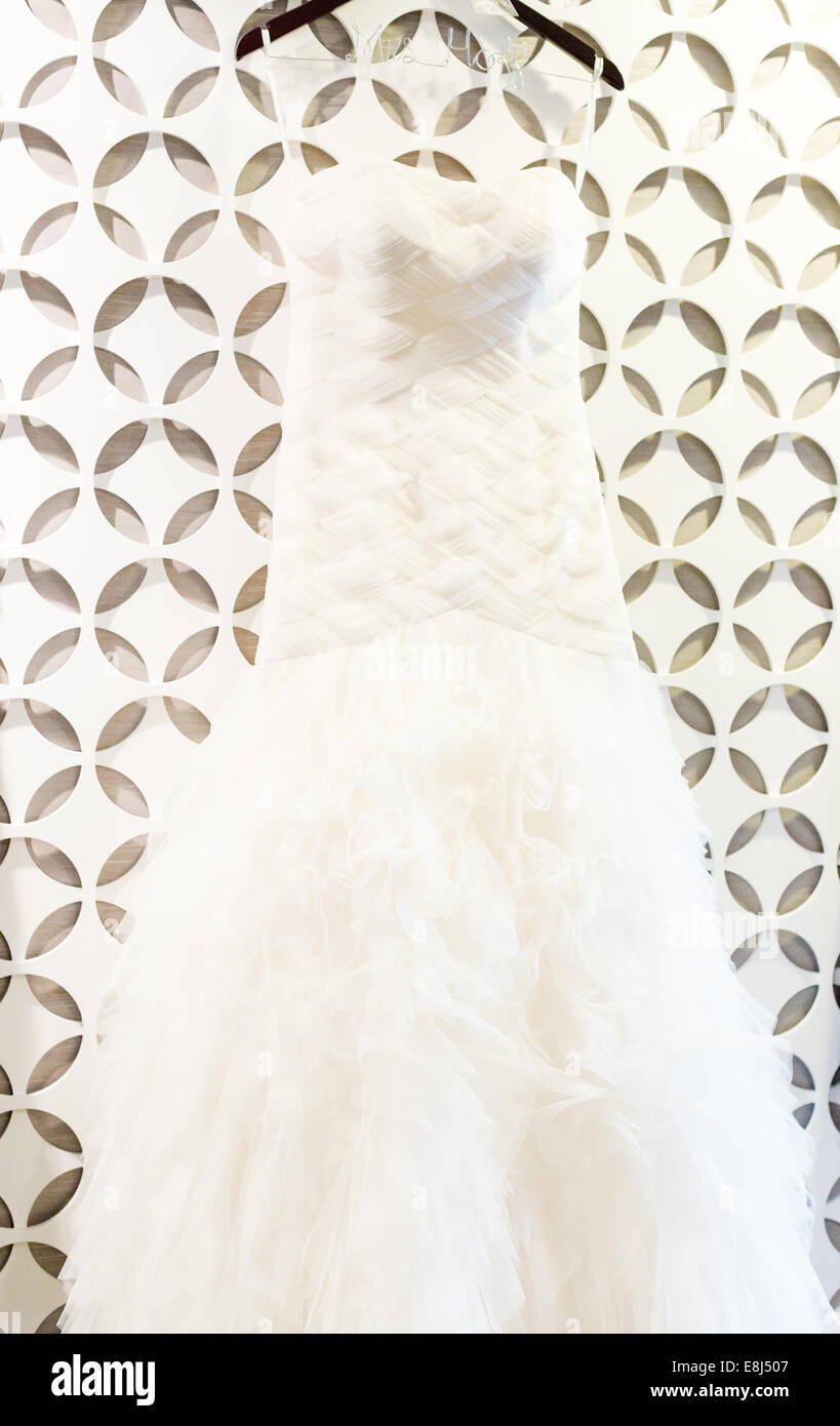 Wedding dress hanging on a white wall with pattern Stock Photo - Alamy