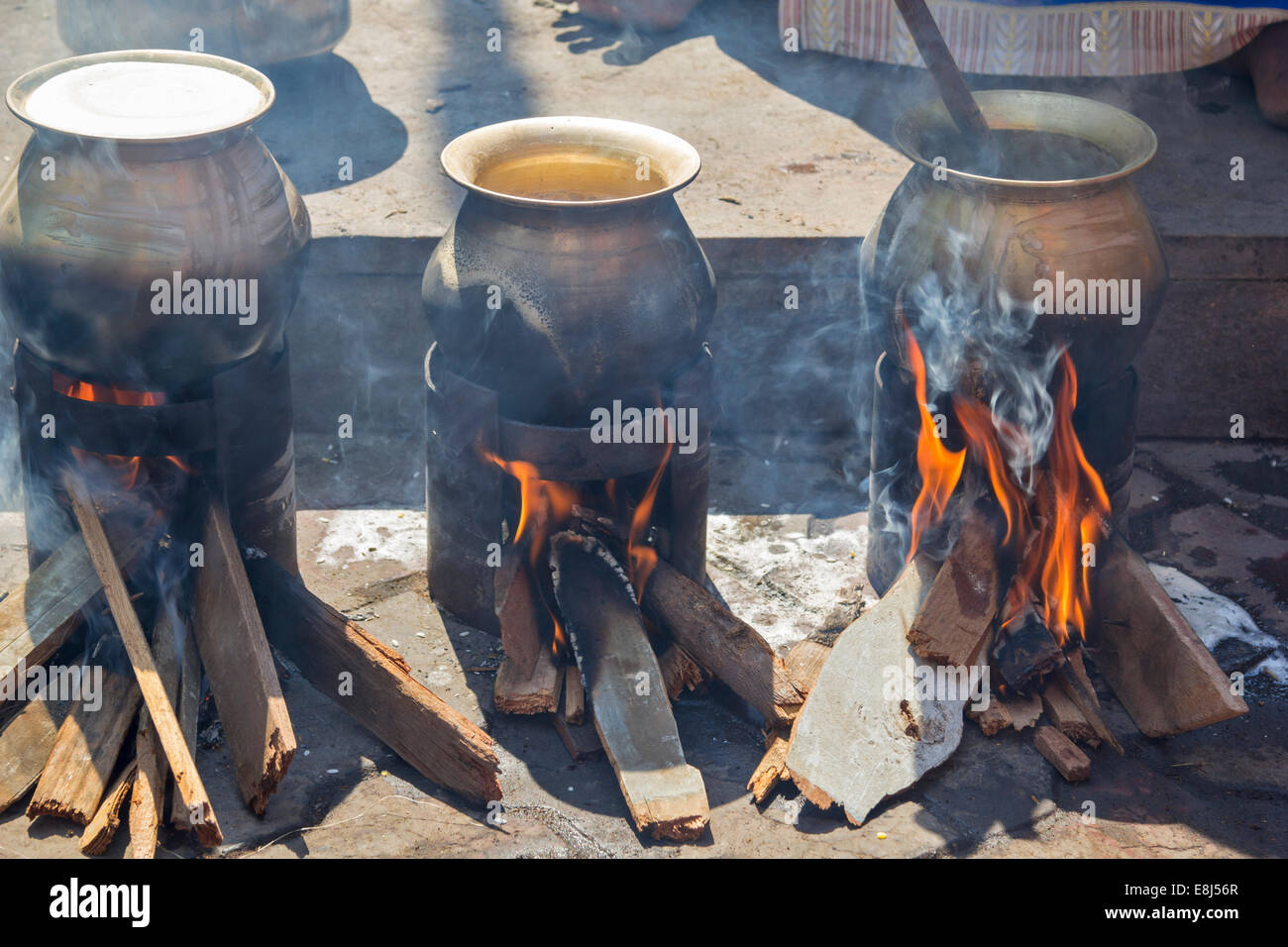 https://c8.alamy.com/comp/E8J56R/food-cooking-in-brass-pots-over-open-fires-in-india-E8J56R.jpg