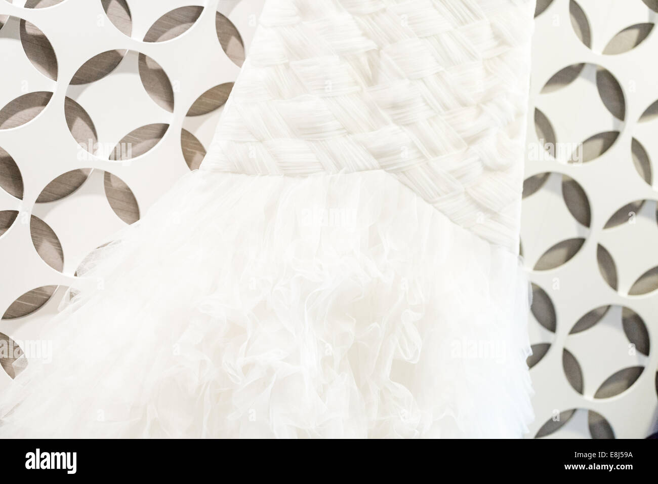 Wedding Dress Hanging On A White Wall With Pattern Stock Photo