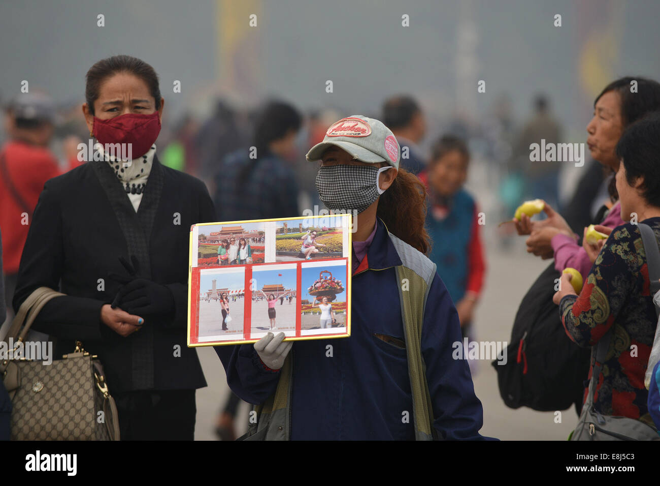 Beijing, China. 9th Oct, 2014. A vendor offering photo service shows photo works to attract tourists at the smog-shrouded Tian'anmen Square in Beijing, capital of China, Oct. 9, 2014. Credit:  Li Xin/Xinhua/Alamy Live News Stock Photo