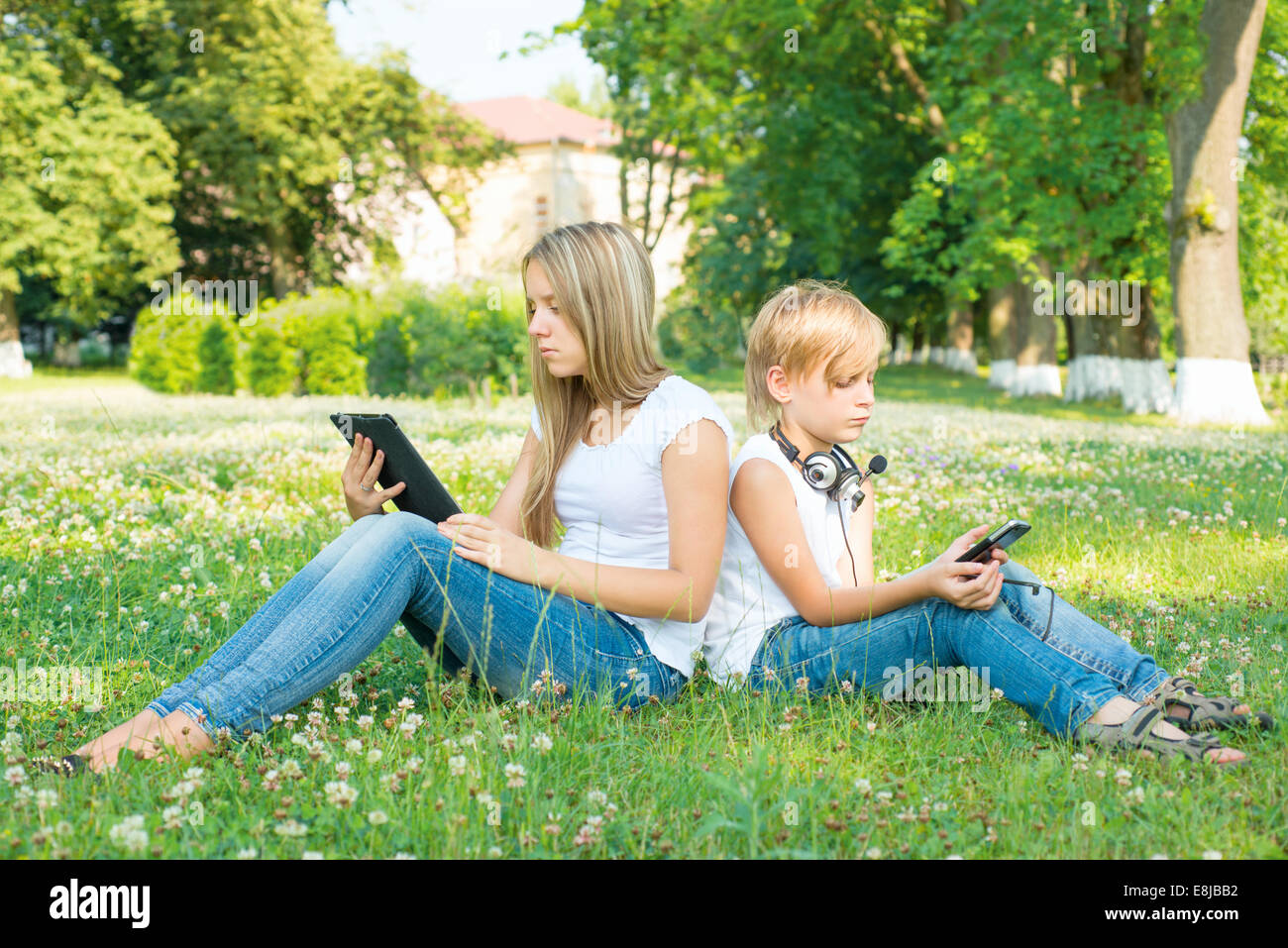 Boy and girl sitting in park with digital tablet Stock Photo - Alamy
