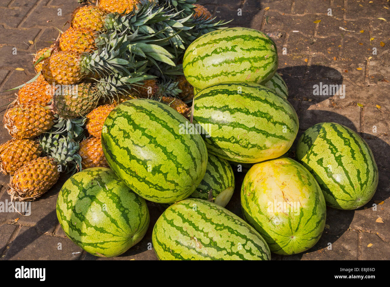 MELONS AND PINEAPPLES FOR SALE ON A PAVEMENT IN INDIA Stock Photo