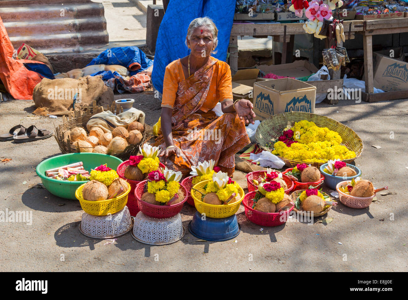 SELLER OF TEMPLE OFFERINGS OR PUJA  IN INDIA TO HINDU GODS BOWLS OF FLOWERS AND COCONUTS Stock Photo