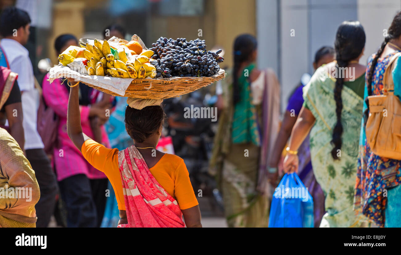 STREET SELLER INDIA CARRYING A BASKET OF GRAPES AND BANANAS ON HER HEAD Stock Photo