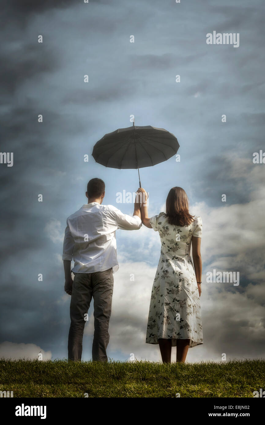 a couple on a meadow with an umbrella Stock Photo