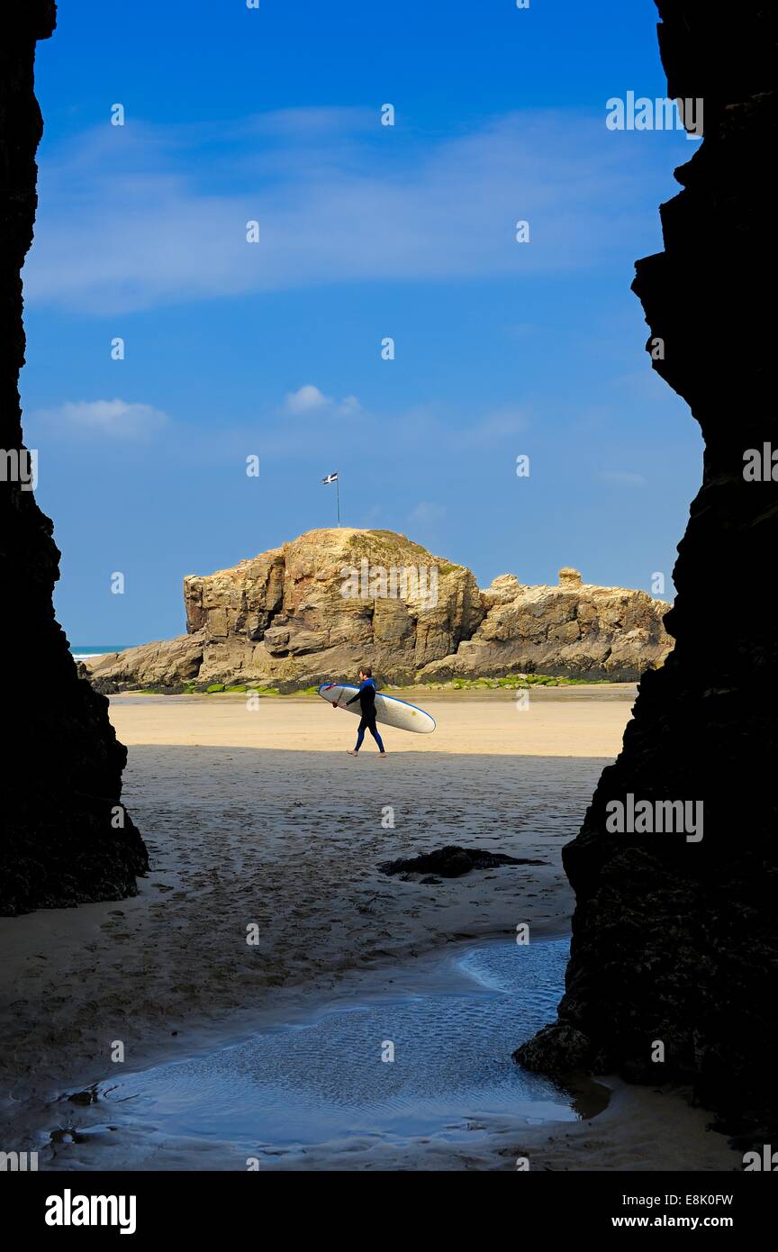 A view of a man carrying a surf board through the archway at Droskyn point Perranporth Cornwall England uk Stock Photo