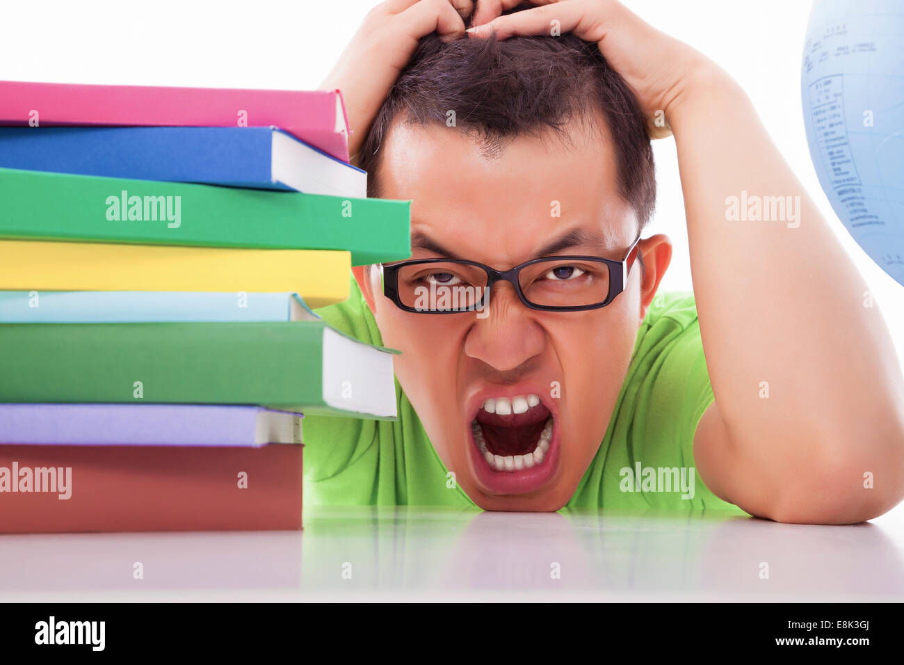 boring and tired young man with many books on the desk Stock Photo