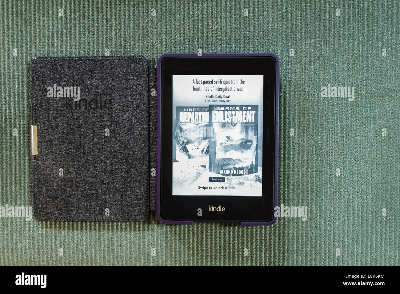 A Paper White Kindle reader lying on green corduroy. Open to a book advertisement, turned on. USA. Stock Photo