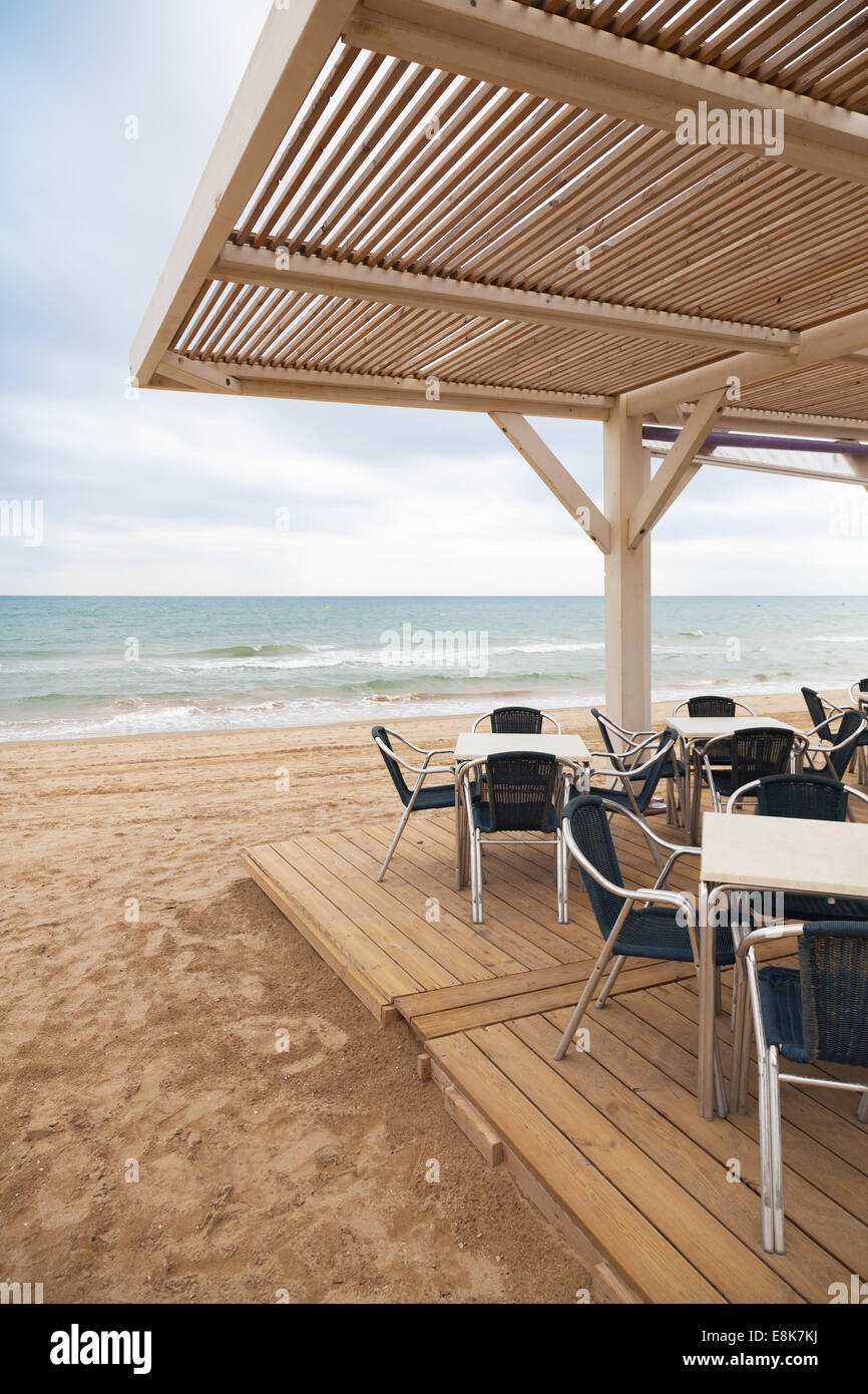 Sea side bar interior with wooden floor and metal armchairs on sandy beach in Spain Stock Photo