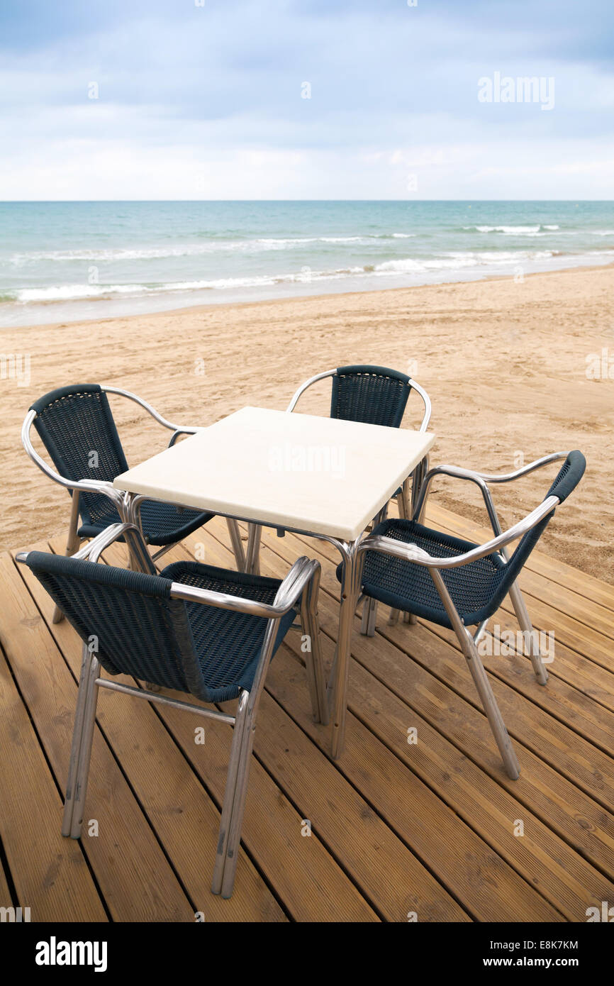 Open space sea side bar interior with wooden floor and metal armchairs on sandy beach Stock Photo